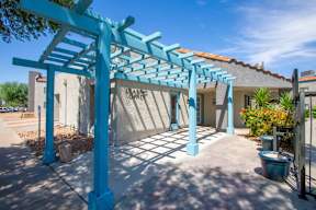 A blue pergola is in front of a building with the words "Leasing Office" on it.