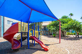 A red slide is in the middle of a playground.