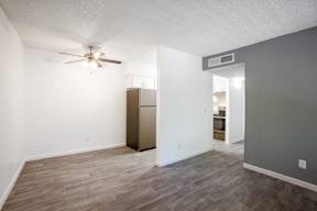 A room with a ceiling fan and a refrigerator.