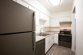 A kitchen with a refrigerator, sink, and stove.