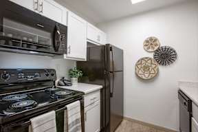A black stove top oven with a white counter top and a black refrigerator in a kitchen.