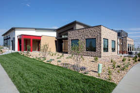 A modern house with a red door and a stone wall.