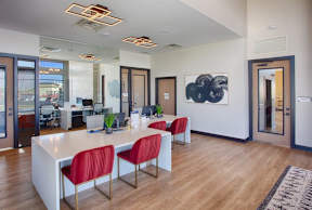 A conference room with a long white table and red chairs.