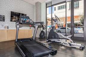 A treadmill and a stationary bike are in a gym.