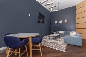A grey wall with a blue sofa and a wooden table.