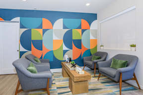 A room with a blue wall and three grey chairs.