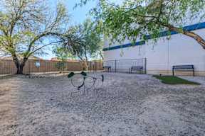 A playground with a swing set and a basketball hoop.