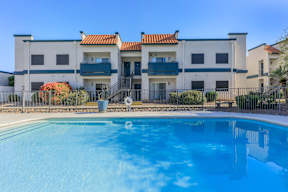 A swimming pool in front of a building with a fence around it.