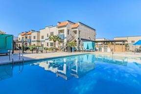 A swimming pool in front of a building with a clear blue sky.