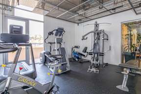 A gym with a treadmill, a stationary bike, and a leg press machine.