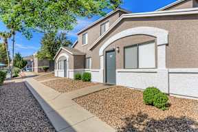 A row of houses with a sidewalk and landscaping.