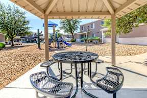 A playground with a table and chairs under a canopy.