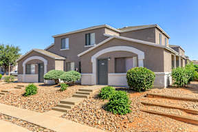 A modern house with a grey exterior and a landscaped front yard.