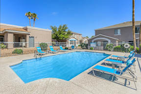 A swimming pool surrounded by lounge chairs and palm trees.