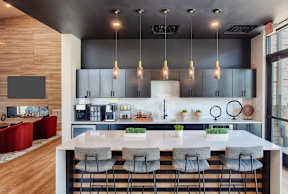 A modern kitchen with a long island and grey barstools.