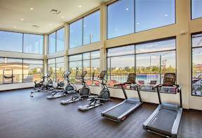 A gym with treadmills and a view of a pool outside.