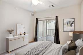 A bedroom with a large bed, a dresser, and a balcony.
