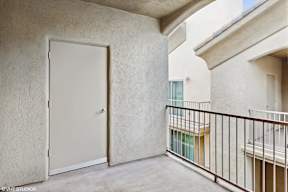 A white door is on the left side of a balcony.