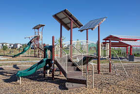 A playground with a green slide and a red and white striped slide.