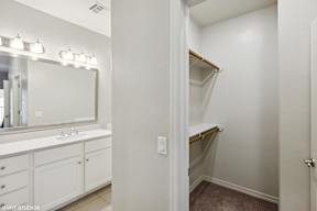 A white bathroom with a sink, mirror, and a closet.