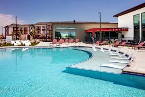 Pool with white lounge chairs in the water.