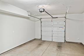 A garage with a white door and a concrete floor.