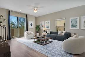 A modern living room with a grey sofa, a white armchair, a coffee table, and a ceiling fan.
