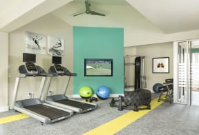 a home gym with a green accent wall and a yellow stripe on the floor