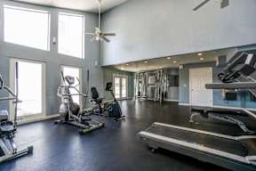 A spacious home gym with a treadmill, exercise equipment, and a ceiling fan.