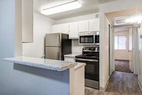 A kitchen with a refrigerator, microwave, oven, and stove.