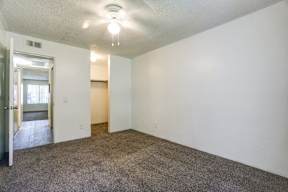 A spacious empty room with carpeted floor and white walls.