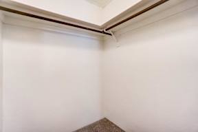 A corner of a room with a brown carpet.