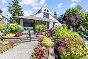 the front yard of a white house with a porch and landscaping