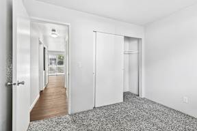 A white room with a grey carpet and a door on the left.