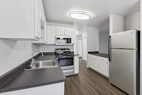 A modern kitchen with white cabinets and stainless steel appliances.