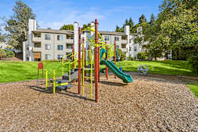 A playground with a green slide and a yellow and red structure.