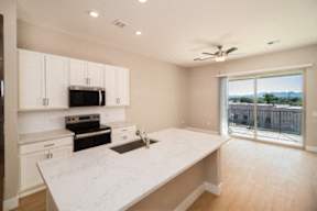 A kitchen with white cabinets and a marble countertop.