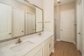 A bathroom with a sink, mirror, and wooden floors.