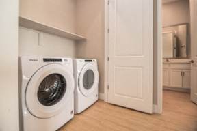 Two white Whirlpool washing machines in a laundry room.