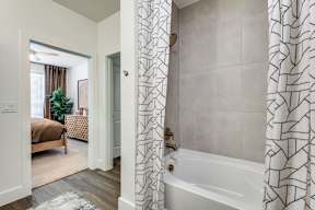 A bathroom with a white tub and a shower curtain with a black and white pattern.