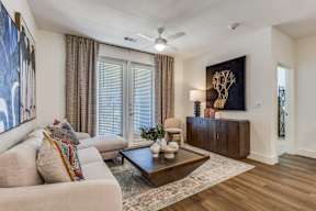 A living room with a beige couch, a coffee table, and a painting on the wall.
