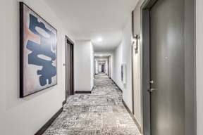 A long hallway with a carpeted floor and doors on both sides.