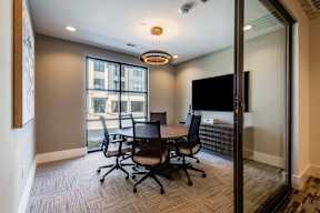 A conference room with a table and chairs and a television.