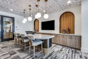 A modern kitchen with a bar area and a television mounted on the wall.