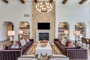 A living room with a stone fireplace and a chandelier.