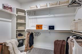 A white closet with clothes and a book on the shelf.