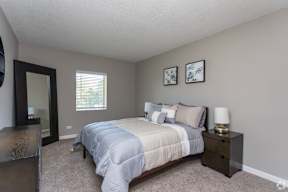 A bedroom with a bed, nightstand, and two pictures on the wall.