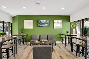 A room with green walls and wooden floors has a couch, chairs, and a table.