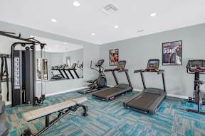A gym with treadmilers, weights, and exercise equipment.