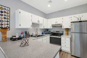 A kitchen with white cabinets and a stainless steel refrigerator.